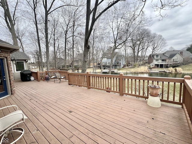 wooden deck featuring a residential view, a water view, and a grill