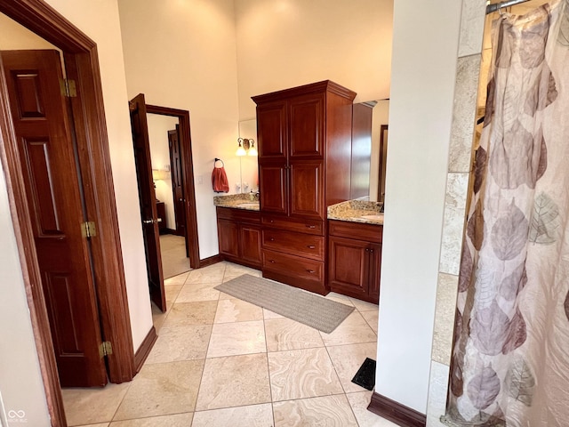 bathroom with double vanity, a high ceiling, a sink, and a shower with curtain