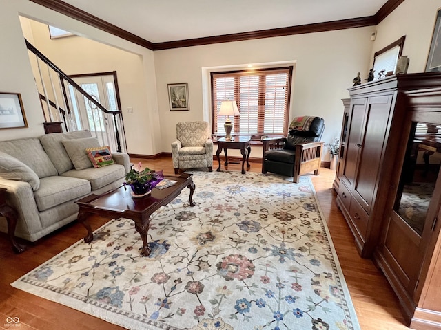 living area with ornamental molding, light wood-type flooring, stairway, and baseboards