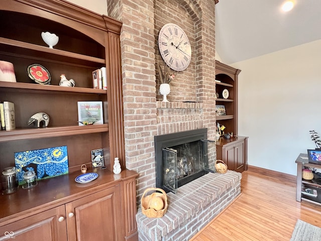 living room with lofted ceiling, built in features, baseboards, a brick fireplace, and light wood finished floors