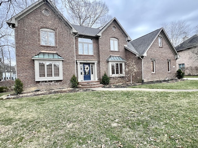 view of front of home with roof with shingles, brick siding, and a front lawn