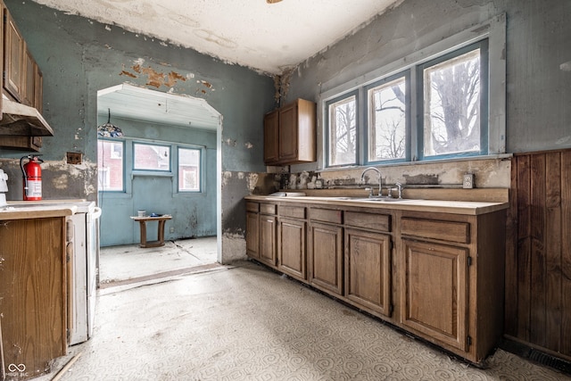 kitchen with light countertops, brown cabinetry, and a sink