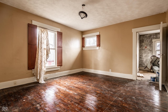 unfurnished room featuring baseboards, a textured ceiling, and hardwood / wood-style flooring