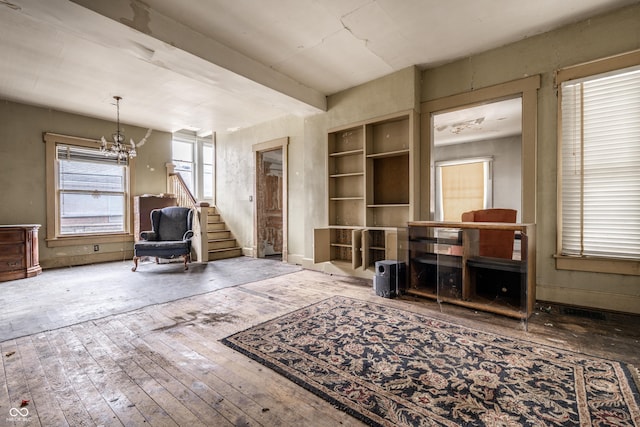 living area with stairs, beam ceiling, wood-type flooring, and a chandelier