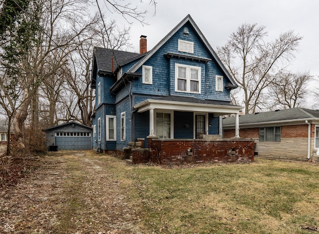 view of front of property with a chimney, covered porch, a front yard, and an outdoor structure