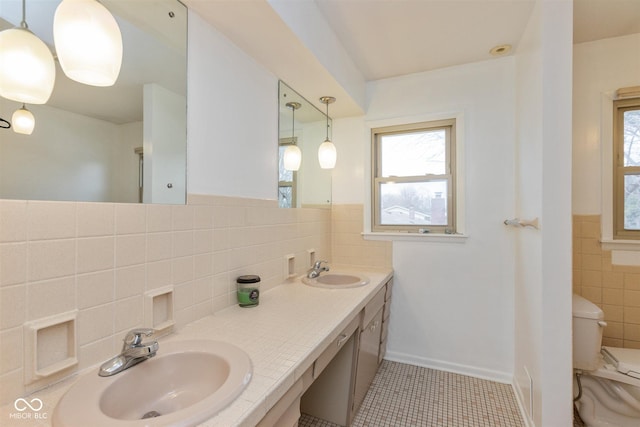 bathroom featuring tile patterned flooring, a sink, tile walls, and toilet