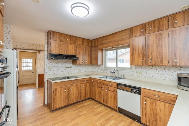 kitchen with black electric stovetop, stainless steel microwave, a sink, dishwasher, and extractor fan