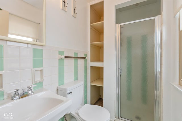 full bath featuring toilet, a shower stall, tile walls, and a sink