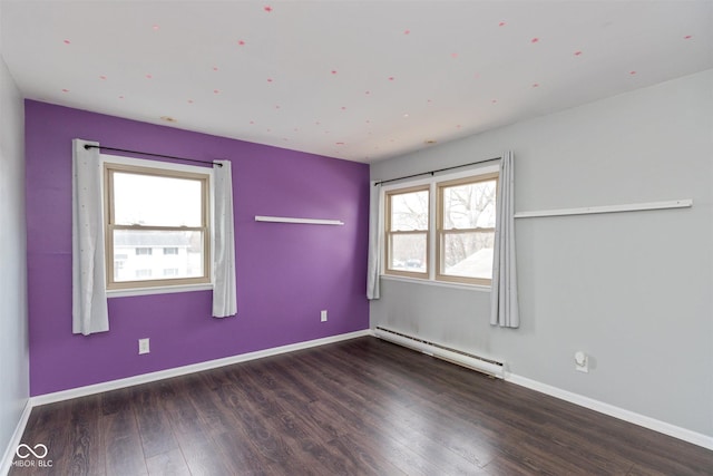 spare room with a baseboard radiator, baseboards, and wood finished floors