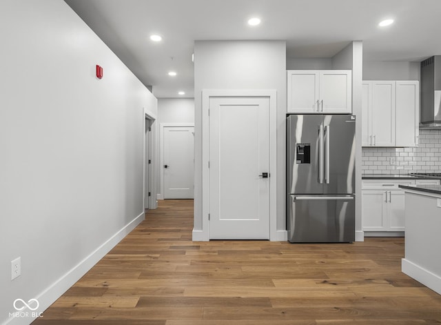 kitchen with decorative backsplash, light wood-type flooring, stainless steel fridge, and white cabinets