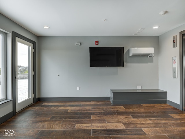 unfurnished living room with an AC wall unit, recessed lighting, wood finished floors, and baseboards