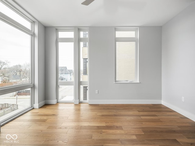 empty room with a healthy amount of sunlight, baseboards, and wood finished floors