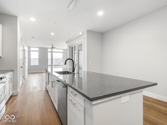 kitchen with recessed lighting, a sink, stainless steel dishwasher, a large island, and light wood-type flooring