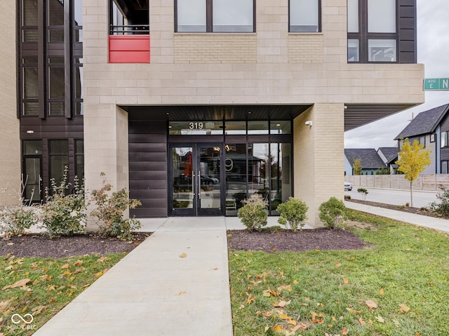 view of exterior entry featuring french doors and brick siding