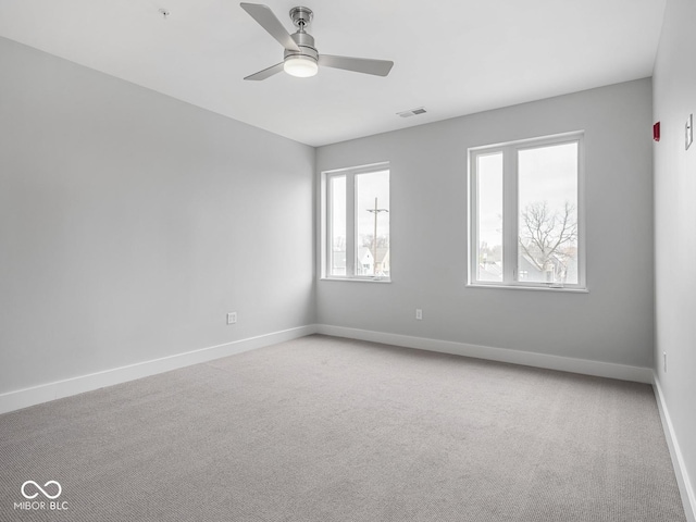 empty room with light carpet, ceiling fan, visible vents, and baseboards