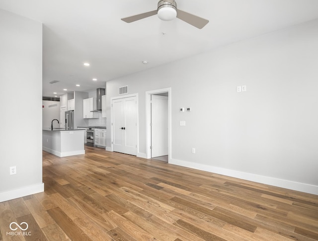 unfurnished living room with recessed lighting, visible vents, light wood-style floors, a sink, and ceiling fan