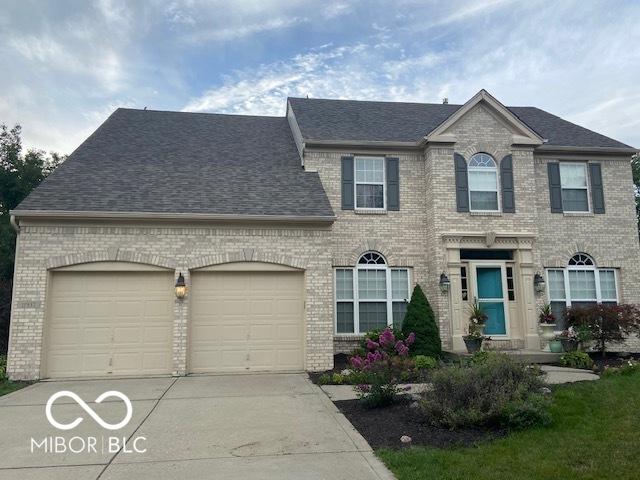 view of front of home featuring a garage, roof with shingles, concrete driveway, and brick siding