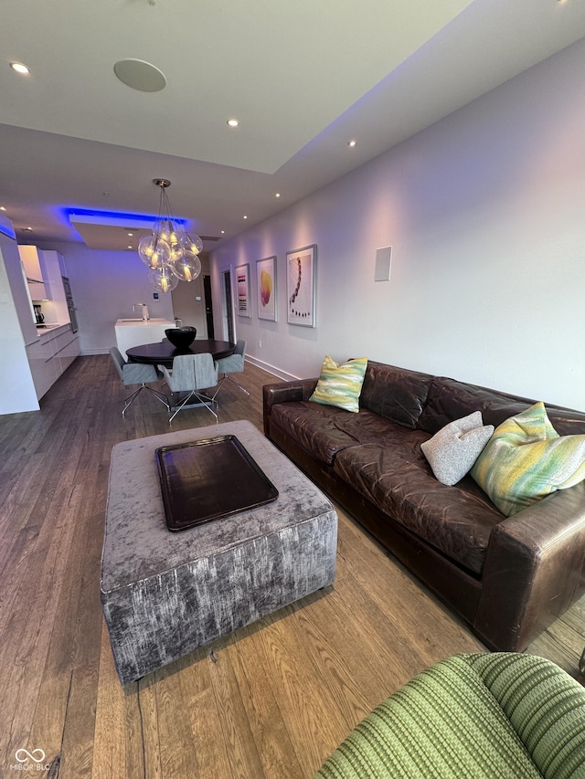 living area featuring a notable chandelier, baseboards, hardwood / wood-style flooring, and recessed lighting