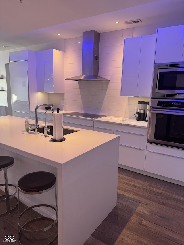 kitchen featuring visible vents, wall chimney exhaust hood, modern cabinets, appliances with stainless steel finishes, and backsplash