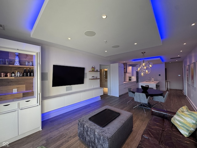 living room with an inviting chandelier, a tray ceiling, dark wood finished floors, and recessed lighting