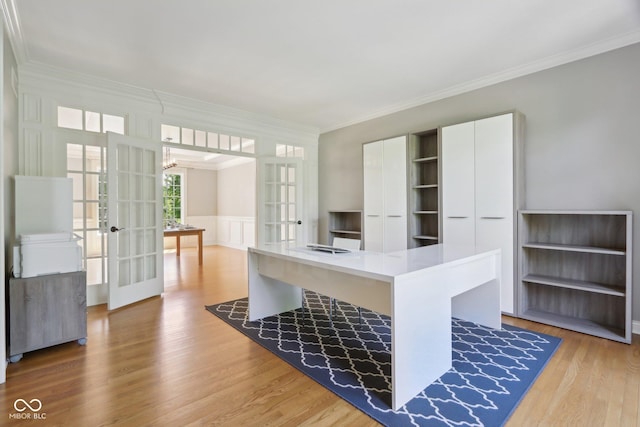 unfurnished office featuring french doors, ornamental molding, light wood-style flooring, and a wainscoted wall