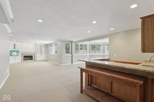 kitchen with recessed lighting, light stone countertops, plenty of natural light, baseboards, and light carpet
