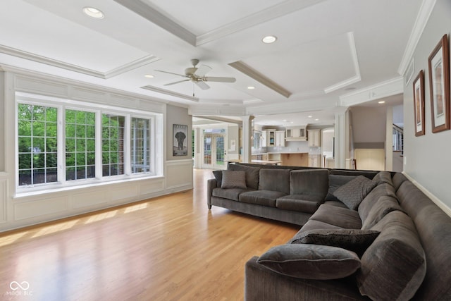 living room with ornamental molding, coffered ceiling, ceiling fan, light wood finished floors, and ornate columns