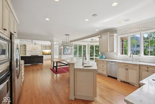 kitchen with stainless steel appliances, open floor plan, a sink, crown molding, and light countertops