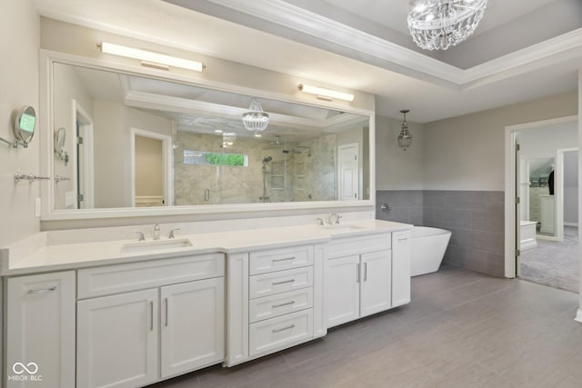 bathroom with tile walls, a chandelier, a stall shower, double vanity, and a soaking tub