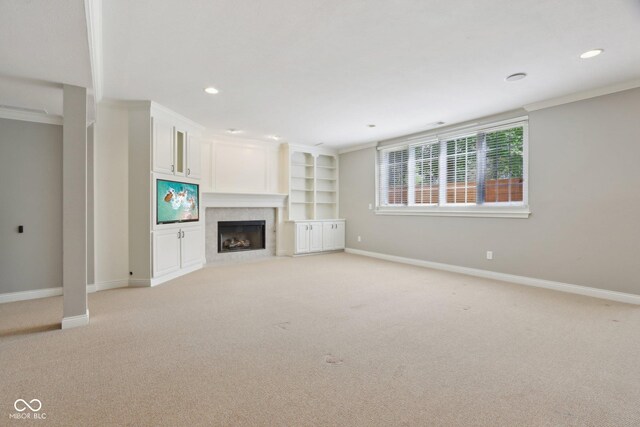 unfurnished living room with light carpet, baseboards, a fireplace with flush hearth, recessed lighting, and crown molding