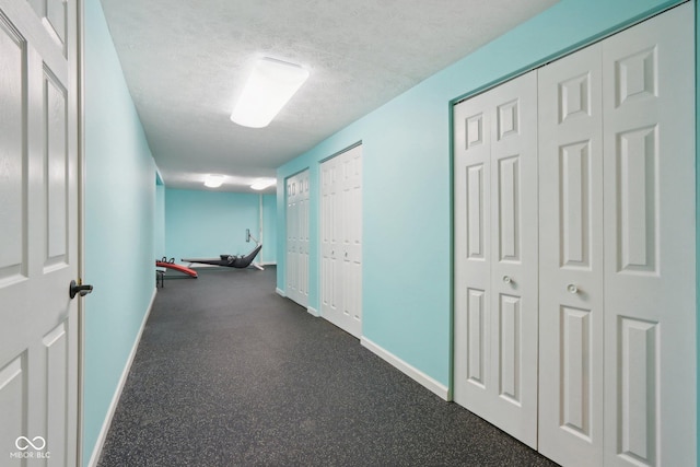 hall with baseboards and a textured ceiling