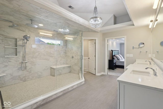 ensuite bathroom with a marble finish shower, double vanity, wood finished floors, and baseboards