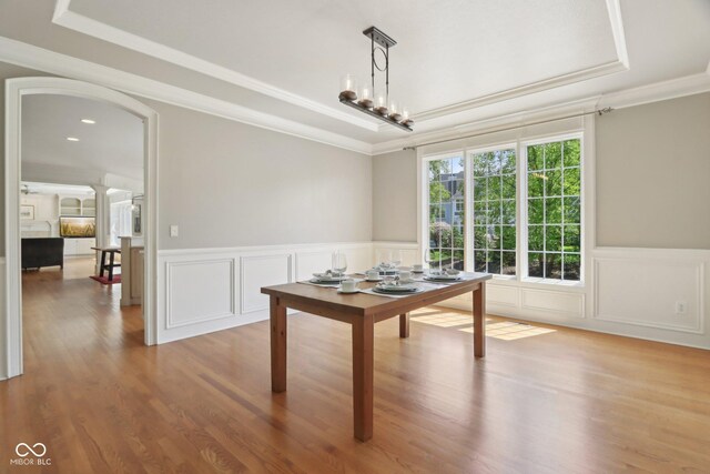 home office with a raised ceiling, ornamental molding, a decorative wall, wood finished floors, and wainscoting