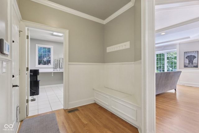 hallway with ornamental molding, a wainscoted wall, and wood finished floors
