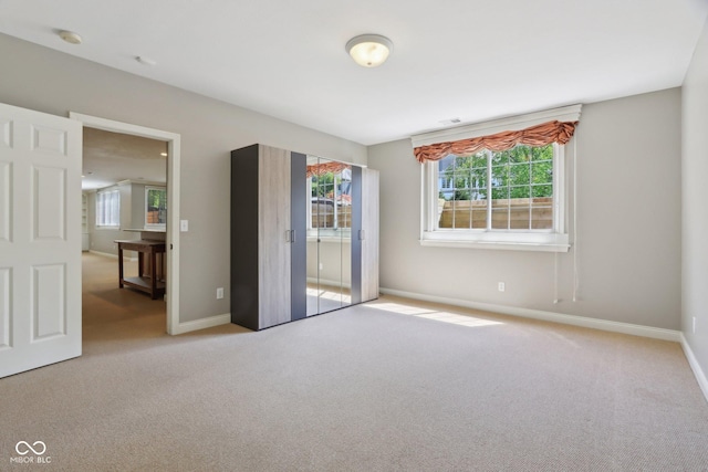 carpeted spare room featuring healthy amount of natural light and baseboards