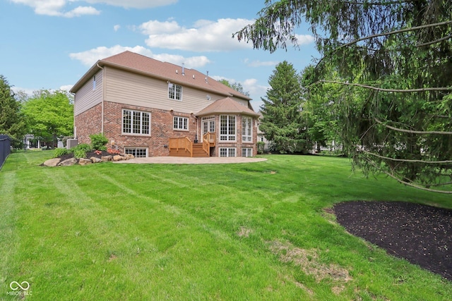 back of property featuring a wooden deck, brick siding, a yard, and a patio area