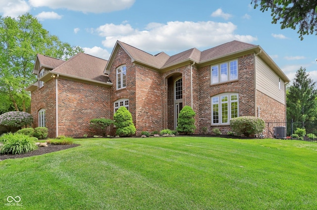 traditional-style home with brick siding, central AC, and roof with shingles