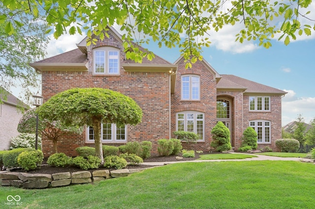 traditional-style house with a front lawn, brick siding, and roof with shingles