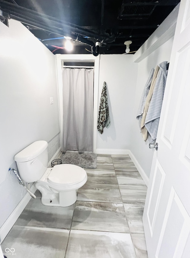 bathroom featuring curtained shower, baseboards, visible vents, and toilet