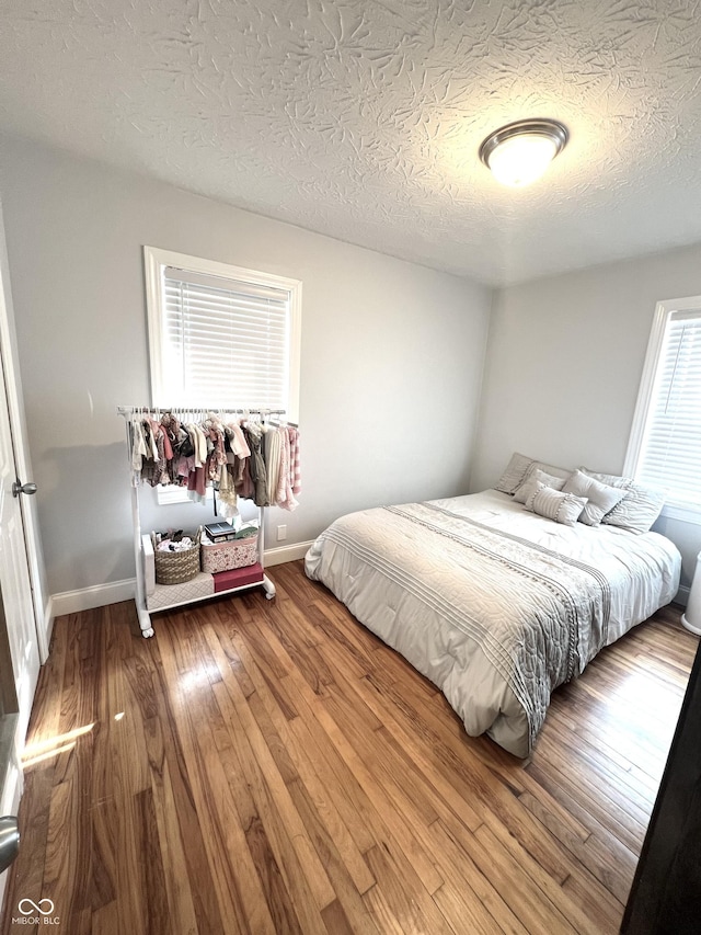 bedroom featuring wood-type flooring, a textured ceiling, and baseboards