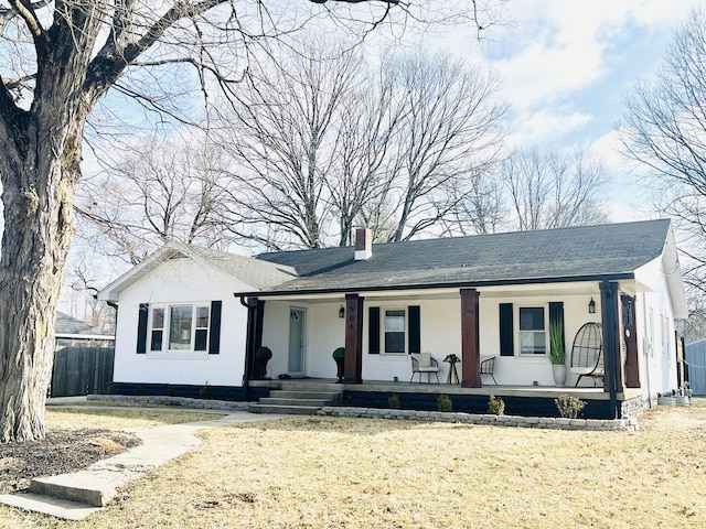 ranch-style house with covered porch, fence, a chimney, and a front lawn