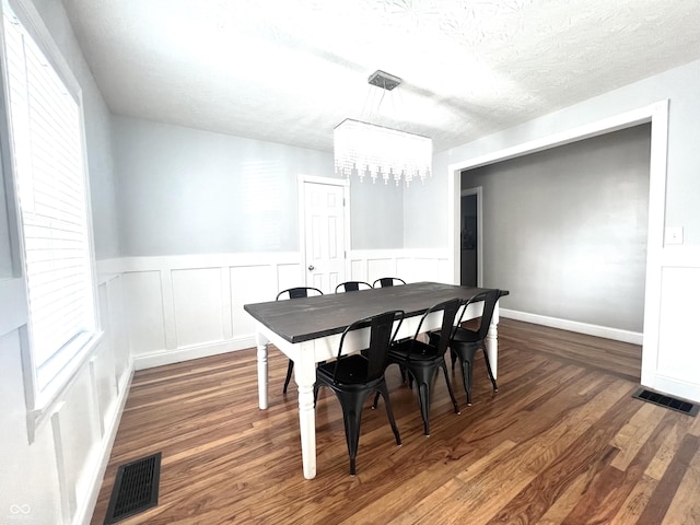 dining room with dark wood-style floors, a notable chandelier, visible vents, wainscoting, and a textured ceiling