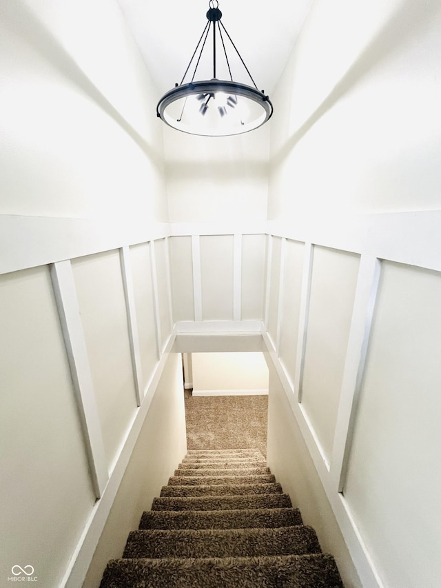 stairs with a wainscoted wall and a decorative wall