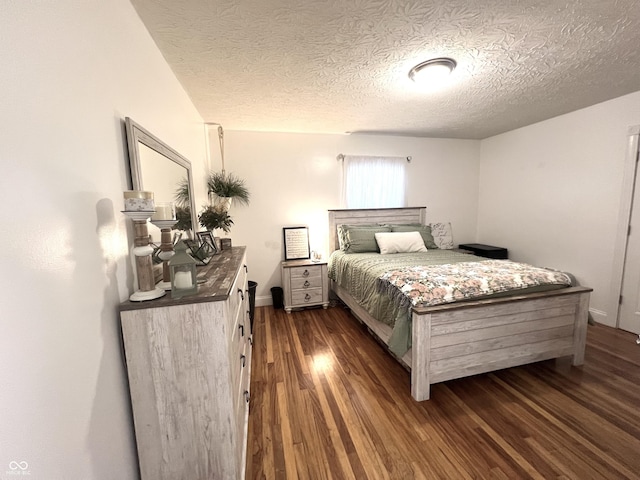 bedroom with dark wood-style floors, a textured ceiling, and baseboards