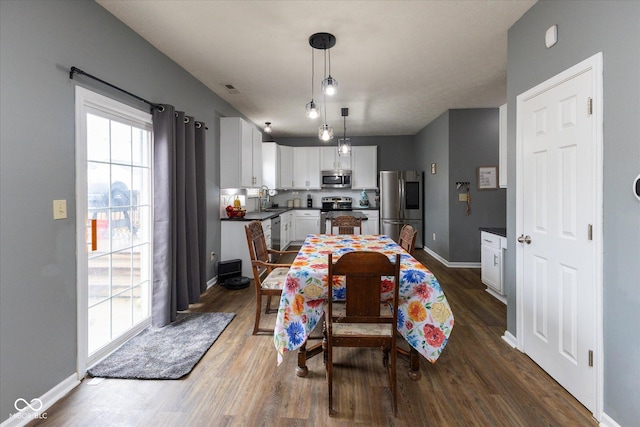 dining area with dark wood-type flooring, visible vents, and baseboards