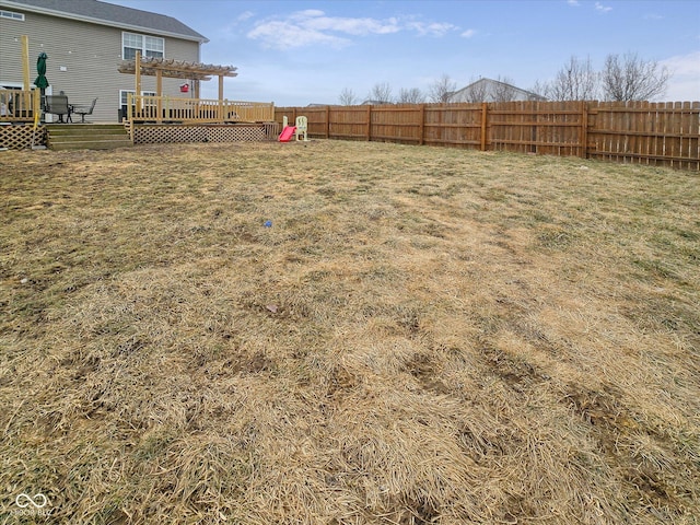 view of yard with a deck, a fenced backyard, and a pergola