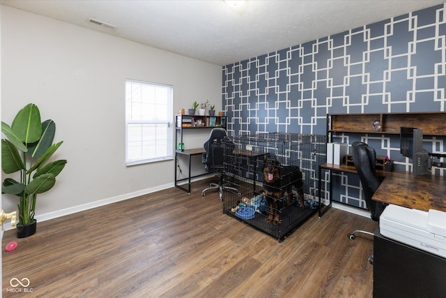 home office featuring visible vents, a textured ceiling, baseboards, and wood finished floors