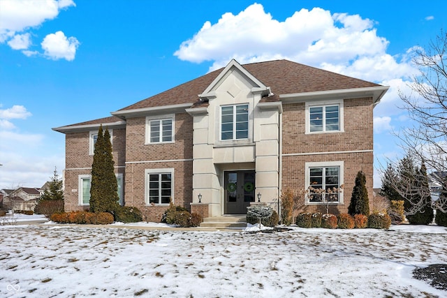 view of front of house with french doors, brick siding, and a shingled roof