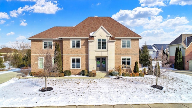 traditional-style home featuring brick siding and roof with shingles