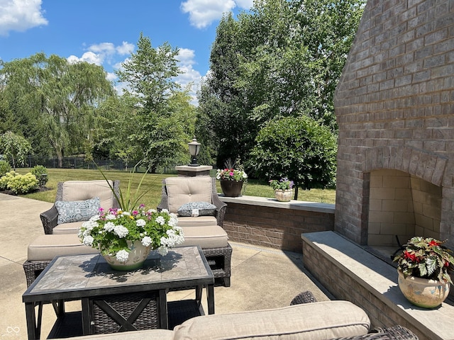 view of patio featuring outdoor dining space, fence, and an outdoor brick fireplace